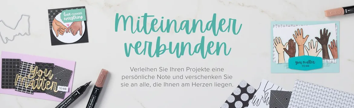 Auf einem hellen Untergrund sind verschiedene Bastelprojekte mit dem Thema „Miteinander verbunden“ angeordnet. Im Zentrum steht der Schriftzug in einer grünen Handschrift, umgeben von Karten und Stempeln. Eine Karte zeigt zwei sich berührende Hände mit dem Text „Love changes everything“, eine andere mehrere Hände unterschiedlicher Hauttöne zusammengefasst mit „you matter to me“. Dazu liegen schwarze Marker, ein Metallstempel in Form einer Silhouette und gestampfte Papierstücke mit Mustern wie Punkten und Raster.