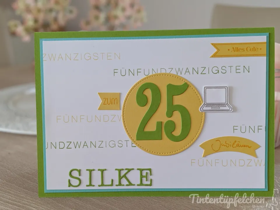 Eine gebastelte Geburtstagskarte mit grüner Rahmenfarbe und gelbem Kreis, der die Zahl 25 in Grün zeigt. Im Hintergrund sind gestempelte Texte wie „Fünfundzwanzigsten“ und ein kleiner Laptop-Stempel sichtbar. Unten steht der Name Silke in grünen Buchstaben.