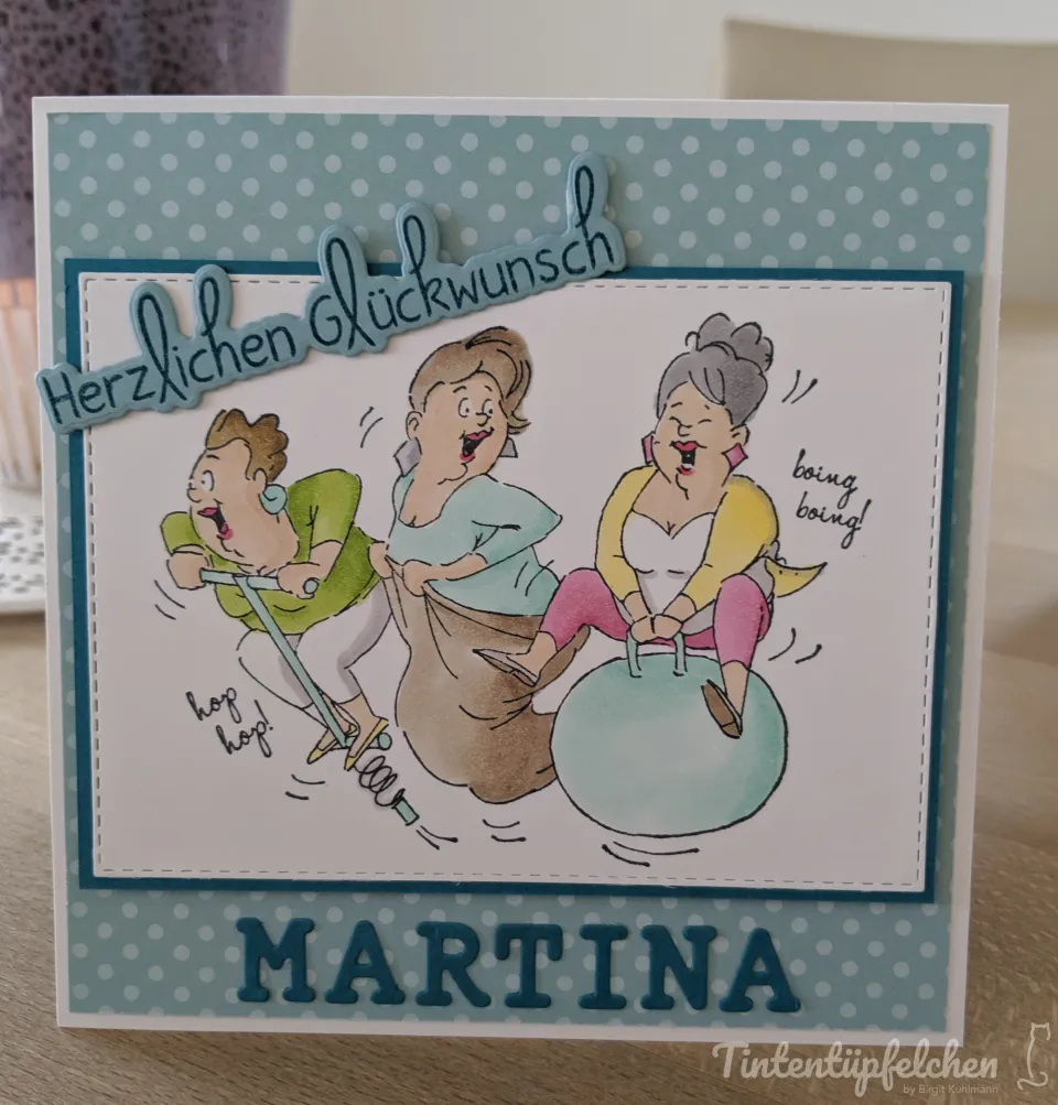 Eine Karte mit dem Schriftzug "Herzlichen Glückwunsch" und drei lachenden Frauen, die auf einem Hüpfball und mit einem Sackhüpfen-Sack spielen. Darunter steht der Name "MARTINA".