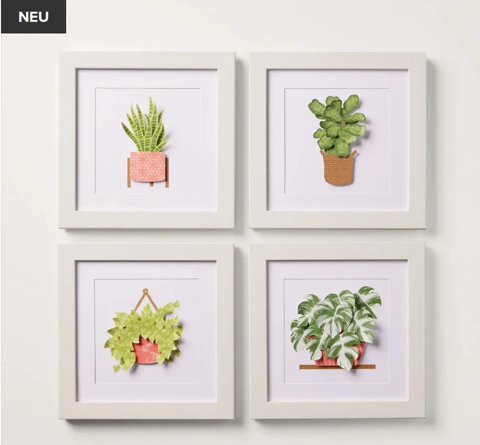 Vier gestempelte Pflanzenillustrationen in weißen Bilderrahmen hängen an einer hellen Wand. Die Motive zeigen verschiedene Grünpflanzen in Töpfen oder Hängern mit unterschiedlichen Farbtönen wie Grün, Rosa und Braun.