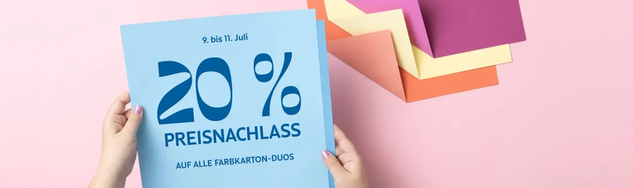 Eine Person hält ein blaues Flyer mit der Aufschrift „20 % PREISNACHLASS AUF ALLE FARBKARTON-DUOS“ für die Zeit vom 9. bis 11. Juli. Im Hintergrund liegen gestapelte farbige Papierkarten in Rosa, Lila, Gelb und Orange auf einem hellrosa Untergrund.