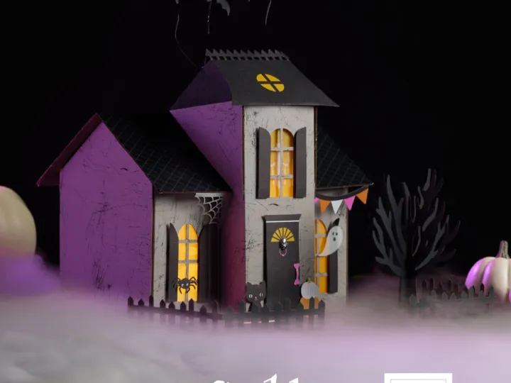 Ein aus Papier und Stempeln gefertigtes Halloween-Spukhaus mit lila und grauen Wänden, gelben Fenstern, schwarzen Dächern und fliegenden Fledermäusen auf dem Dach. Um das Haus herum stehen kleine grüne Bäume, ein weißer Geist an der Wand und eine Spinnweben-Dekoration; im Vordergrund liegt weißes Papier als Nebel.