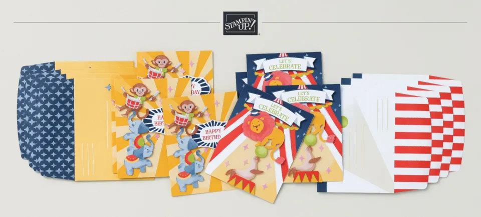 Ein Bastelset mit Zirkus- und Tiermotiven in Gelb, Blau und Rot. Die Karten zeigen gestempelte Affen auf Trommeln, Elefante und einen Löwen mit dem Text „Happy Birthday“ oder „Let’s Celebrate“. Dazu gehören Umschläge mit Sternmuster und Streifen sowie gelbe Papierbögen.