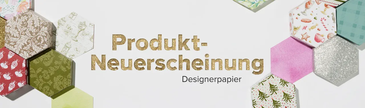 Goldener Text „Produkt-Neuerscheinung Designerpapier" steht zentral auf weißem Hintergrund. Um ihn herum sind hexagonale Papierstücke in verschiedenen Mustern und Farben angeordnet: glänziges Gold, mattes Silber, pastellrosa mit Wasserfarbton, grüne Blätter, rote Motive von Äpfeln sowie ein Muster mit Teebechern und Sternen. Die Hexagone zeigen unterschiedliche Texturen wie Glitter oder Druckmuster.